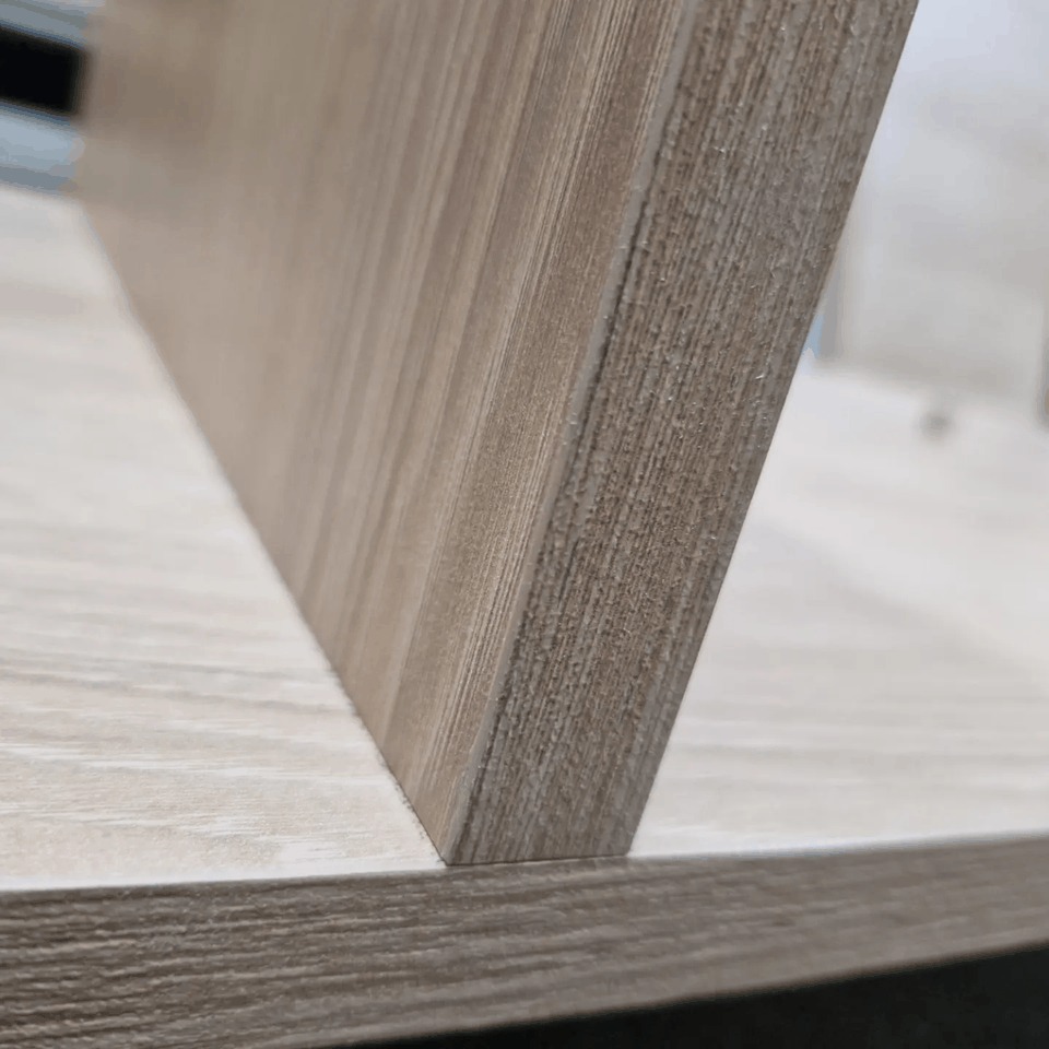 Fragment drewnianej półki z widoczną strukturą drewna i krawędzią, zbliżenie na łączenie elementów.