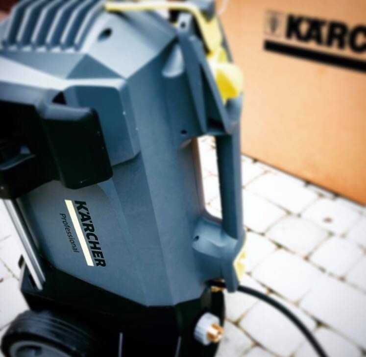 Profesjonalna myjka ciśnieniowa Kärcher Professional na kostce brukowej, z widocznym pudełkiem w tle.