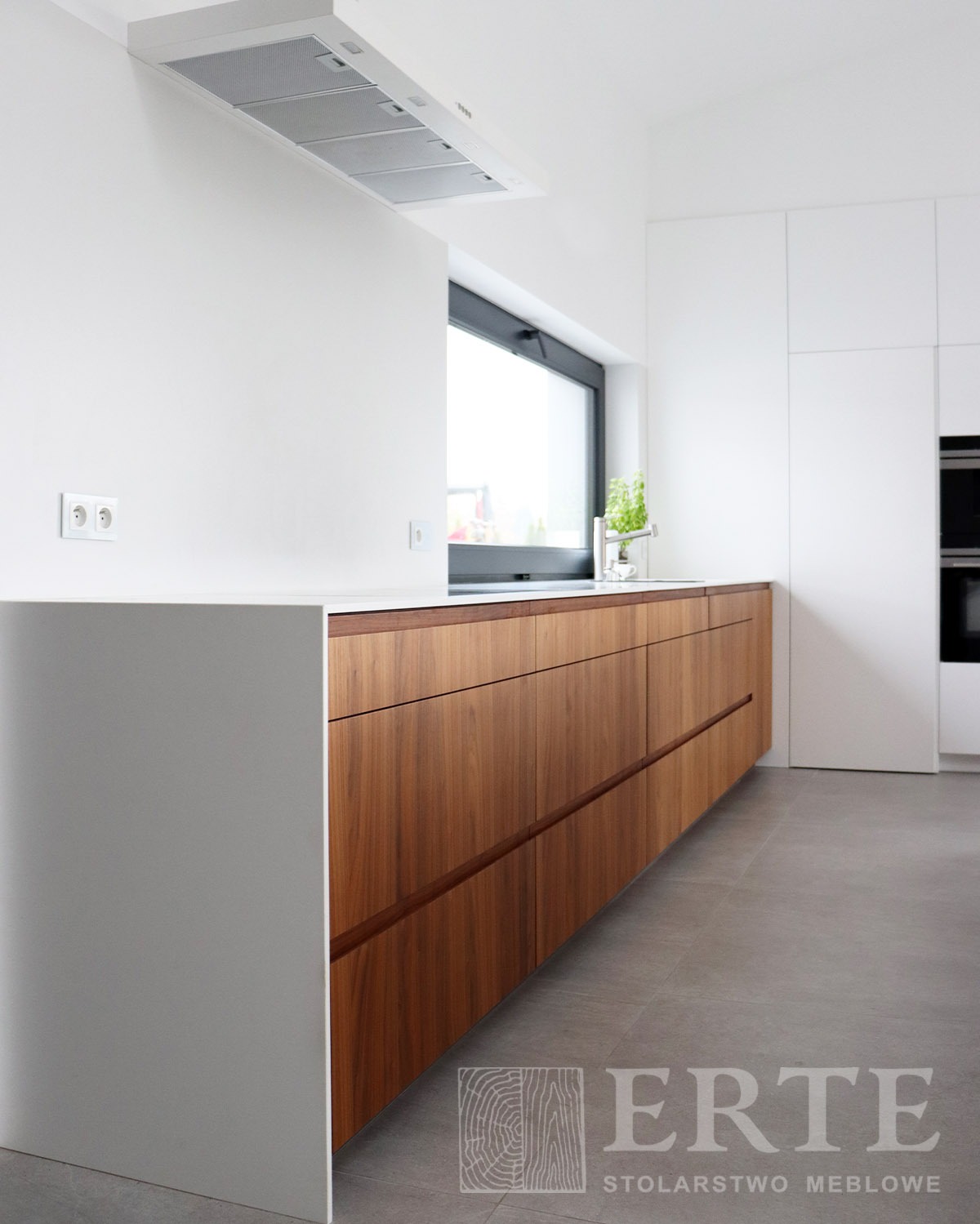 Nowoczesna kuchnia: drewniane fronty dolnych szafek z poziomymi uchwytami, biały blat i wyspa, minimalistyczny okap, szara podłoga.