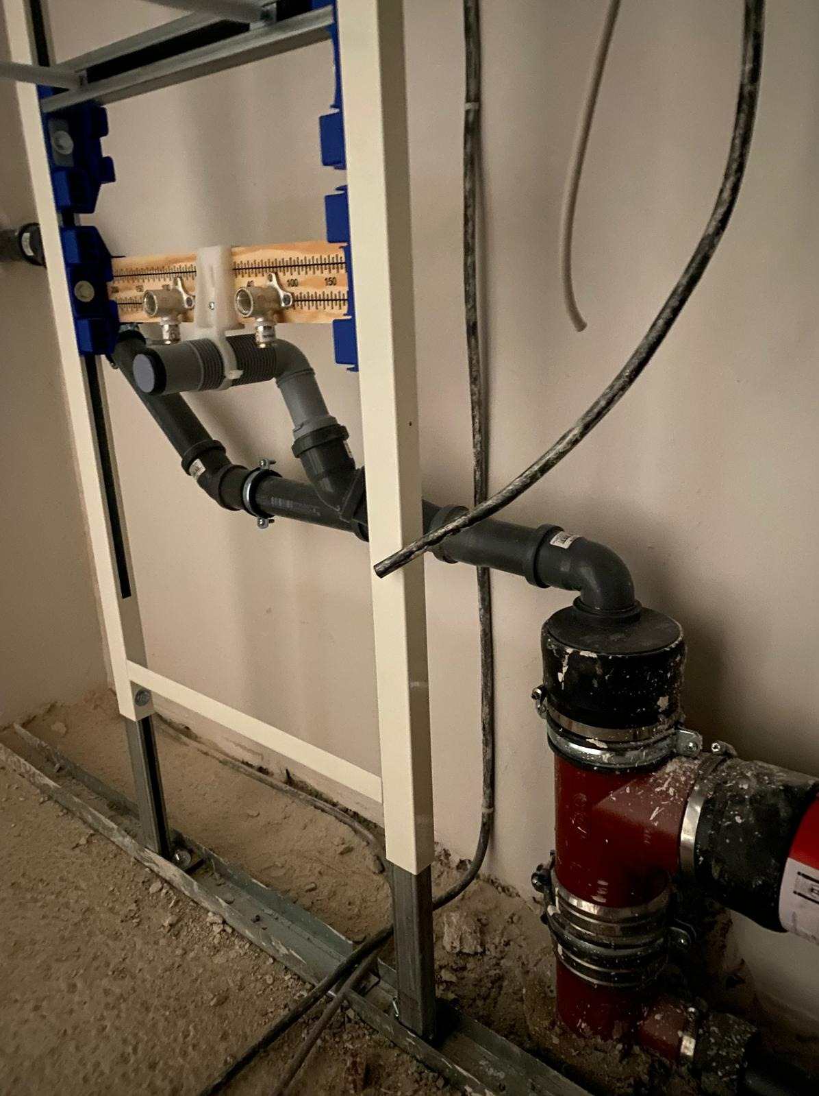 Szczegółowe ujęcie instalacji podtynkowej z rurami i zaworami w trakcie montażu w Szczecinie, widoczne elementy mocujące i fragment podłogi w stanie surowym.