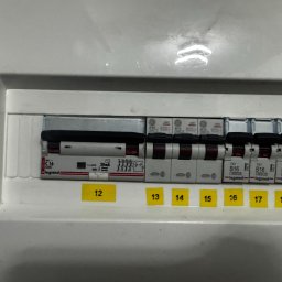 Kastal Electric - Rozdzielnica elektryczna z bezpiecznikami Legrand, oznaczona numerami 12-18 na żółtych naklejkach. Widoczne schematy i oznaczenia na poszczególnych elementach.