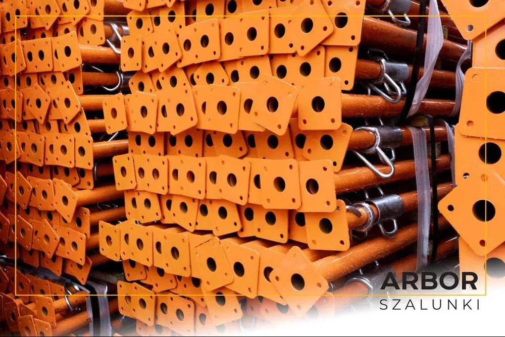 Pomarańczowe stemple budowlane, ułożone w stos, widoczne metalowe elementy mocujące, Wyryki-Połód.