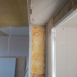 MAX-BUD JAKUB ZARZYŃSKI - Ocieplenie ściany wełną mineralną w metalowym stelażu, widoczne płyty gipsowo-kartonowe i pianka montażowa. Etap prac wykończeniowych wewnątrz budynku.