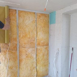 MAX-BUD JAKUB ZARZYŃSKI - Ocieplanie ściany wełną mineralną, widoczne profile i instalacja elektryczna. Częściowo położone płyty gipsowe. Prace wykończeniowe wewnątrz budynku.