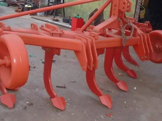 Czerwony kultywator rolniczy z zębami, widok z boku, świeżo pomalowany, gotowy do użycia.