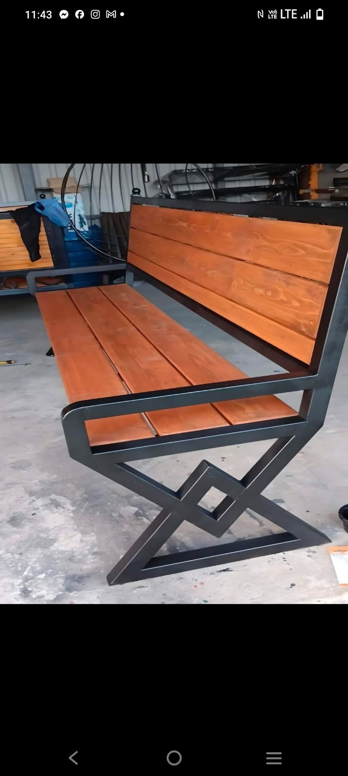 Gotowa ławka parkowa z drewnianym siedziskiem i oparciem, osadzona na metalowej konstrukcji o geometrycznym wzorze