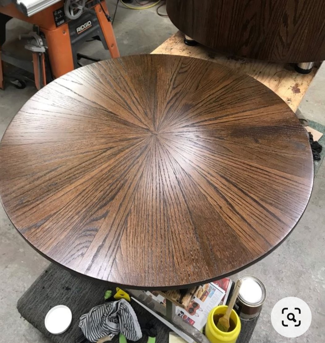 Okrągły, drewniany blat stolika kawowego z promienistym wzorem słojów, widoczne narzędzia i materiały do wykończenia drewna.