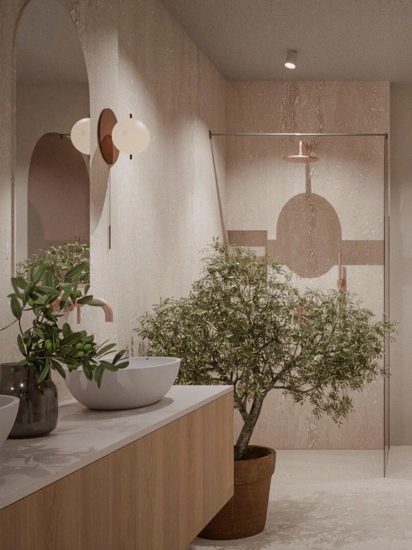 Beżowa łazienka z umywalką nablatową, armaturą w kolorze miedzi, geometryczną grafiką na szklanej kabinie prysznicowej i drzewkiem oliwnym w donicy.