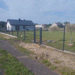 Kuba mąkosa - Nowoczesne ogrodzenie panelowe z bramką na betonowej podmurówce, widok z zewnątrz posesji. W tle dom jednorodzinny i drzewa.