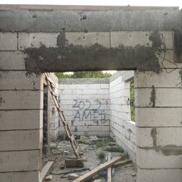 Kuba mąkosa - Surowy stan budynku w trakcie budowy z białych bloczków, widoczne ślady zaprawy, drabina oparta o ścianę, napis '2022 AMEL' na wewnętrznej ścianie.