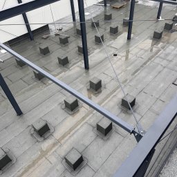 Dachyix Sp.Z.O.O - Płaski dach pokryty papą z licznymi kominkami wentylacyjnymi w kształcie sześcianów, widok z góry na metalową konstrukcję budynku.