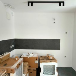 PROFIHOME & OLEKSANDR MELESHKO - Wnętrze kuchni w trakcie prac wykończeniowych: widoczne kartony ze sprzętem AGD (Bosch, Franke) pod ścianą z fragmentem położonych ciemnych płytek, surowa instalacja elektryczna na ścianie i suficie.