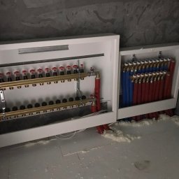 F.U.H. EFEKT ADAM GAWLAK, STANISŁAW GAWLAK SPÓŁKA CYWILNA - Rozdzielacz instalacji podłogowej w białej obudowie, widoczne rury czerwone i niebieskie, oraz skrzynka sterownicza firmy Tech dla wielu pomieszczeń, montaż w trakcie prac wykończeniowych.