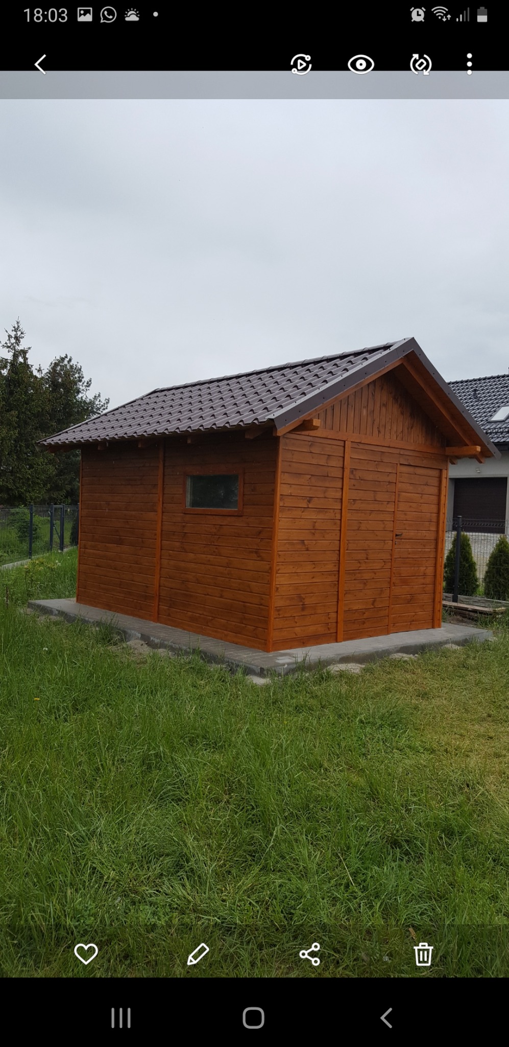 Nowy, drewniany domek narzędziowy z brązowym dachem z blachodachówki, usytuowany na betonowej podmurówce, otoczony zielonym trawnikiem.