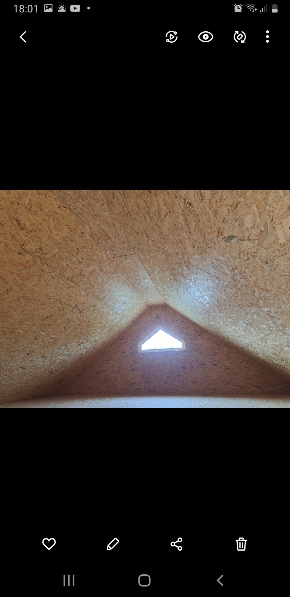 Poddasze wykończone płytami OSB z trójkątnym oknem dachowym w szczycie, widok od wewnątrz.