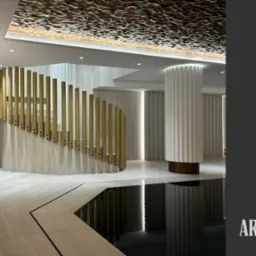 Eleganckie wnętrze: schody z złotymi balustradami, kolumna z żłobieniami i dekoracyjny sufit z oświetleniem. Minimalistyczny design z elementami luksusu.