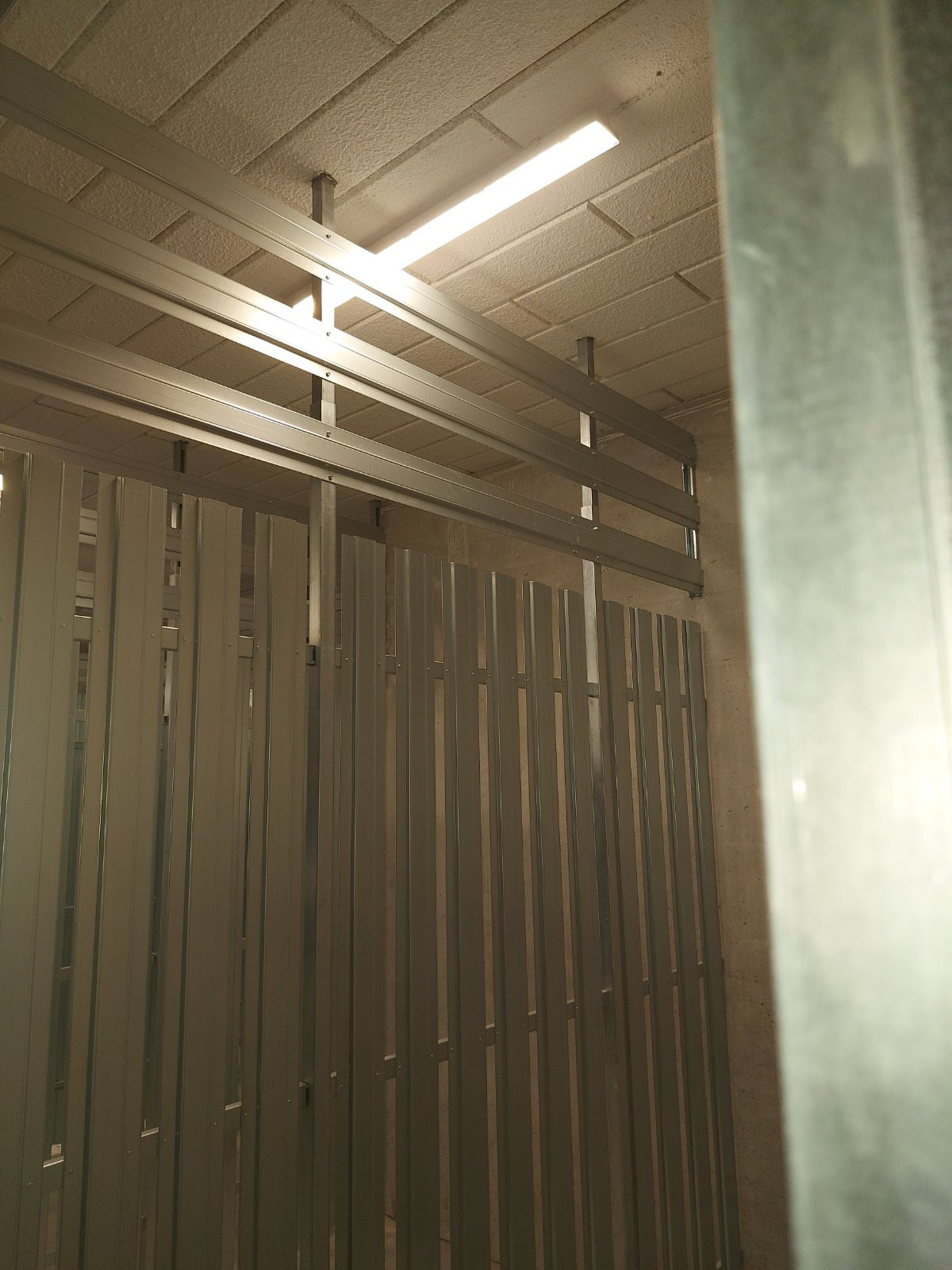 Metalowa konstrukcja sufitu podwieszanego z widocznym oświetleniem liniowym, w trakcie montażu. Widoczne profile i płyty gipsowe.