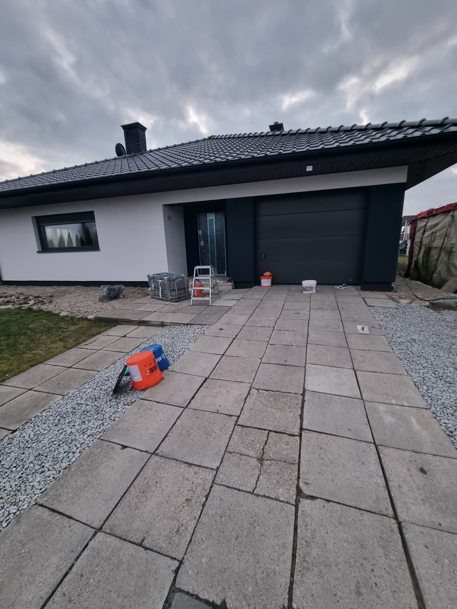 Dom jednorodzinny w Gledzianowie po częściowym malowaniu elewacji, widoczne przygotowane materiały, drabina i wiaderka z farbą.