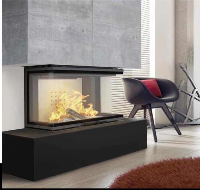 Nowoczesny narożny kominek z czarną obudową i paleniskiem, płomienie widoczne przez szklaną szybę. W tle betonowa ściana i designerskie krzesło.