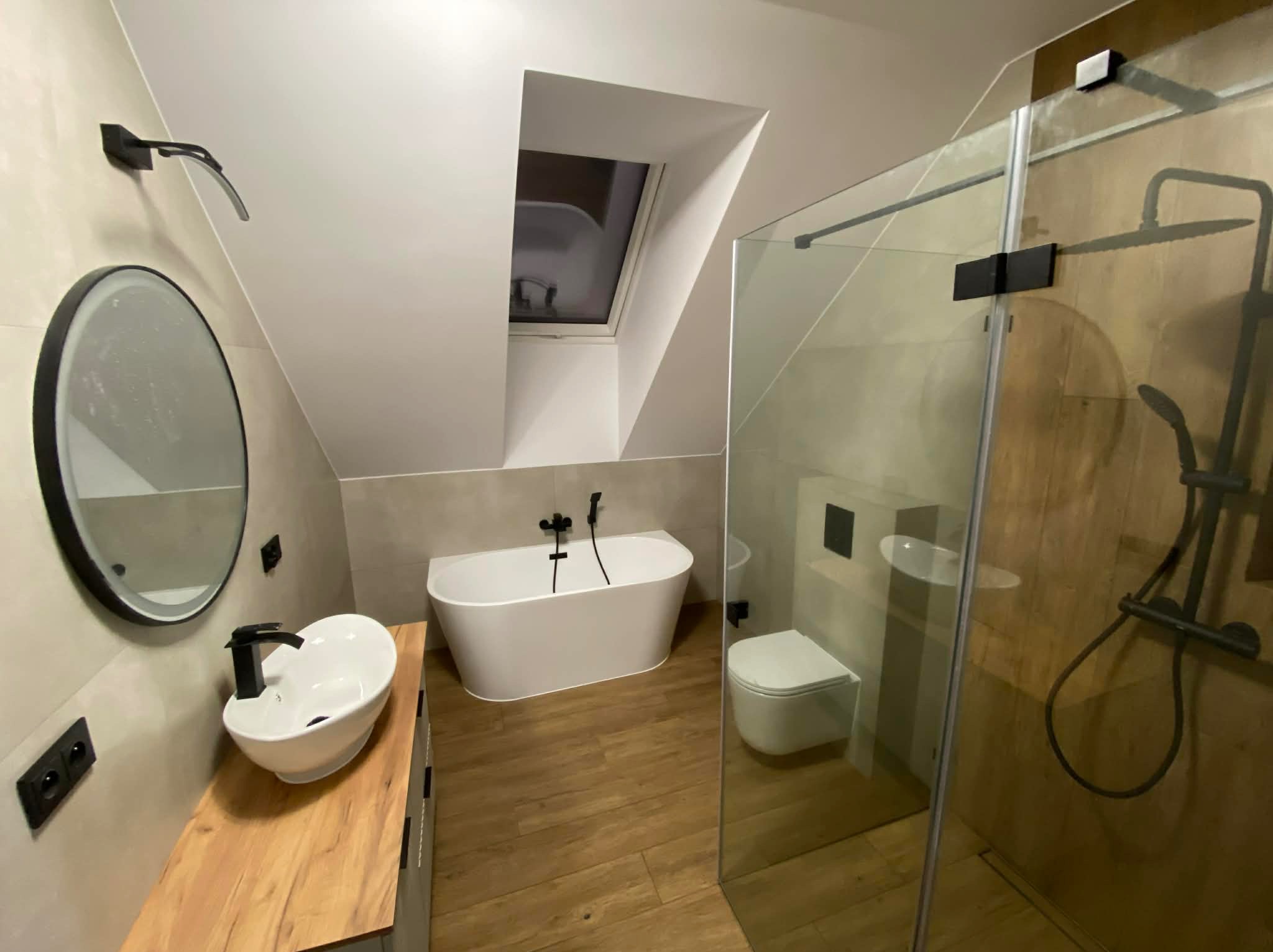 Nowoczesna łazienka na poddaszu w Łomży z drewnianą podłogą, owalną umywalką na blacie, wanną wolnostojącą i kabiną prysznicową ze szklaną ścianą.