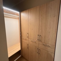 MatWood Design - Jasna, drewniana szafa wnękowa z oświetleniem LED wewnątrz. Widoczny fragment wnętrza szafy z półkami. Minimalistyczne, srebrne uchwyty.