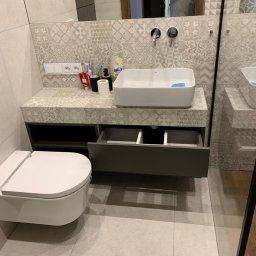 MatWood Design - Nowoczesna łazienka z wiszącą szafką pod umywalką, otwartą szufladą i wzorzystymi płytkami na ścianie. Minimalistyczny design, jasne kolory i funkcjonalne rozwiązania.