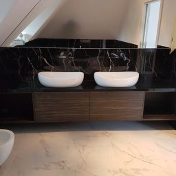 MatWood Design - Nowoczesna łazienka na poddaszu z dwoma białymi umywalkami nablatowymi, czarnym marmurem na ścianie i szafką z ciemnego drewna. Widoczny bidet i marmurowa podłoga.