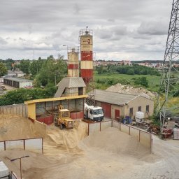 Wytwórnia Materiałów Budowlanych Zdzisława Szczepańska - Widok z góry na teren betoniarni z silosami, stertami piasku i żwiru, ładowarką, betonomieszarką oraz elementami infrastruktury energetycznej w tle.