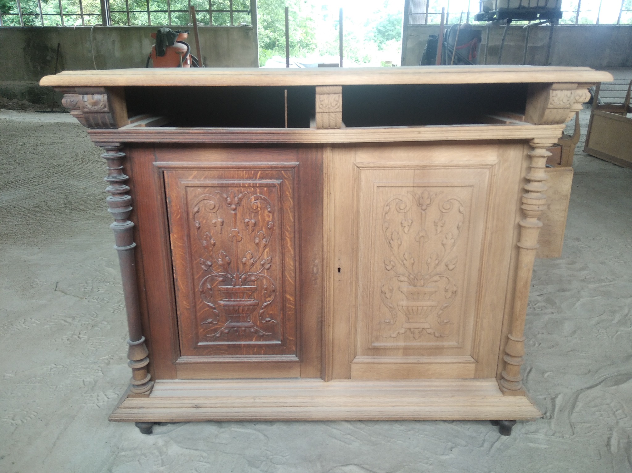 Renowacja antycznego kredensu w Wilkowie: widoczna różnica po częściowym usunięciu starej powłoki, ukazująca jaśniejsze drewno i detale rzeźbienia.