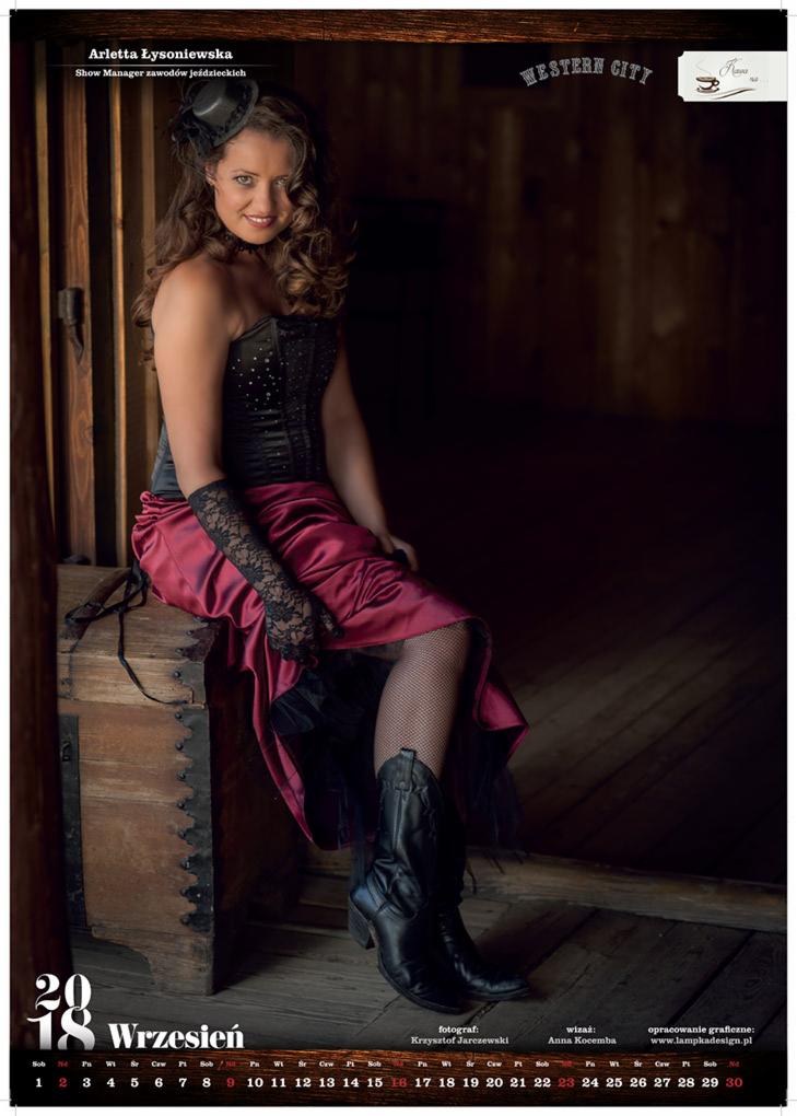Kobieta w stylizowanej sesji zdjęciowej, ubrana w gorset, czerwoną spódnicę i kowbojki, siedząca na drewnianej skrzyni, z kalendarzem na dole zdjęcia.