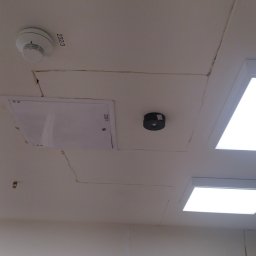 AlexBud - Sufit z widocznymi pęknięciami na łączeniach płyt, czujnik dymu, czujnik ruchu, klapa rewizyjna i lampy LED, widoczne ślady po pracach wykończeniowych