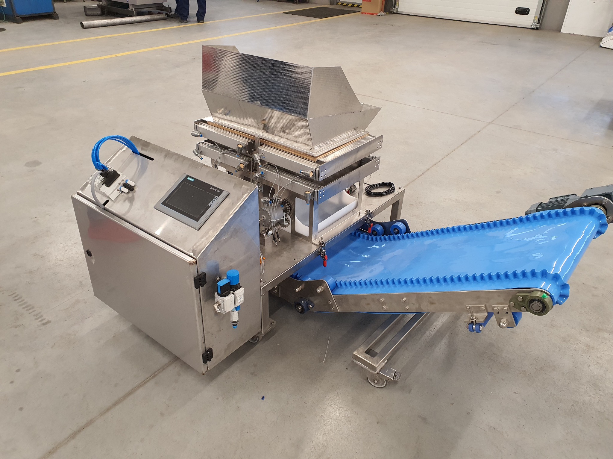 Maszyna przemysłowa ze stali nierdzewnej z niebieskim przenośnikiem taśmowym, widok z góry, Gdynia. Detal: panel sterowania Siemens.