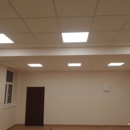 Anatolii Kardynal - Zakończony montaż sufitu podwieszanego kasetonowego z oświetleniem LED w jasnym pomieszczeniu z oknem i drzwiami. Widoczna równa powierzchnia sufitu.