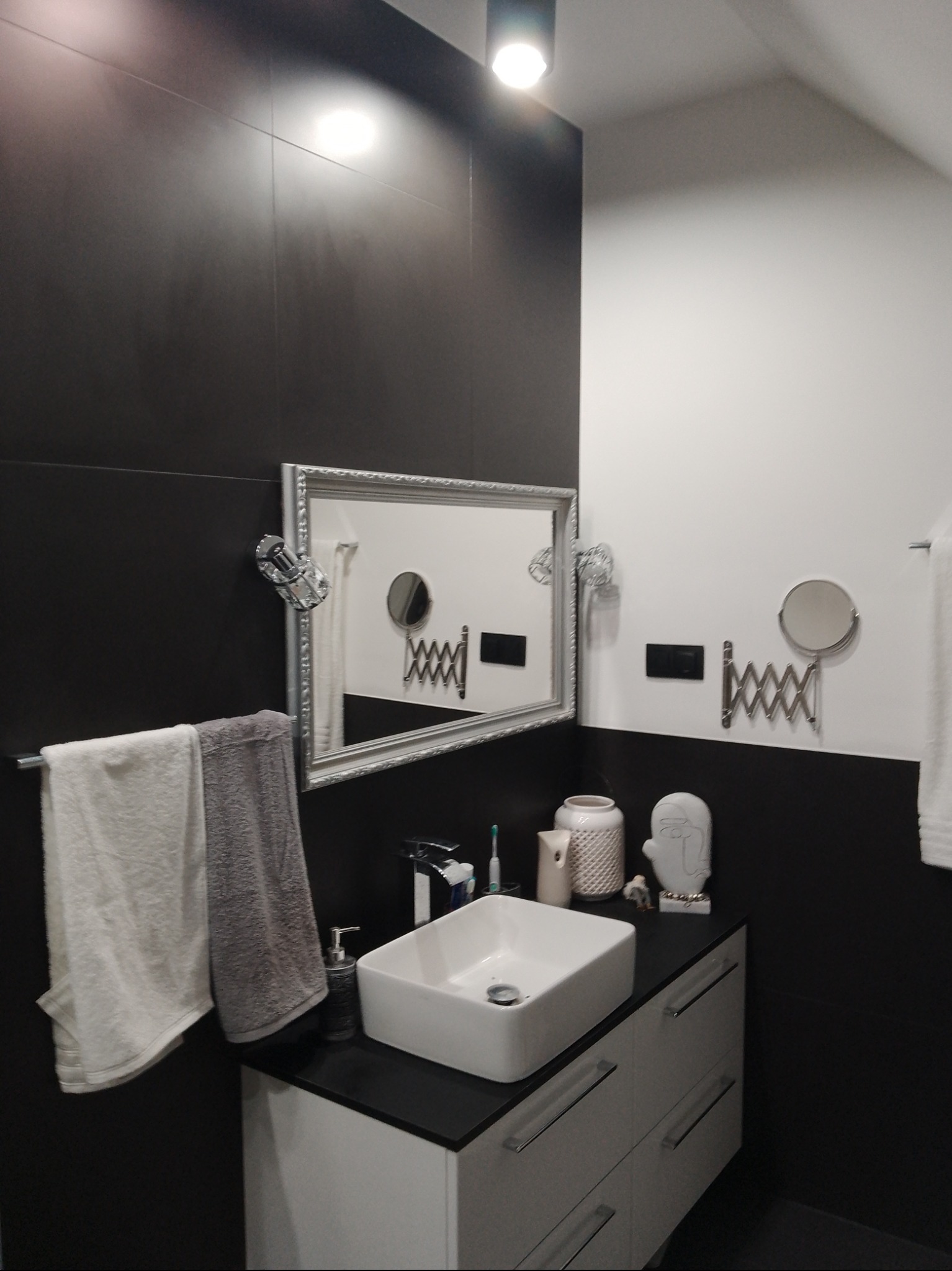 Nowoczesna łazienka w Godzieszach Wielkich z czarno-białymi płytkami, umywalką nablatową i lustrem w ozdobnej ramie. Minimalistyczny design i funkcjonalne dodatki.