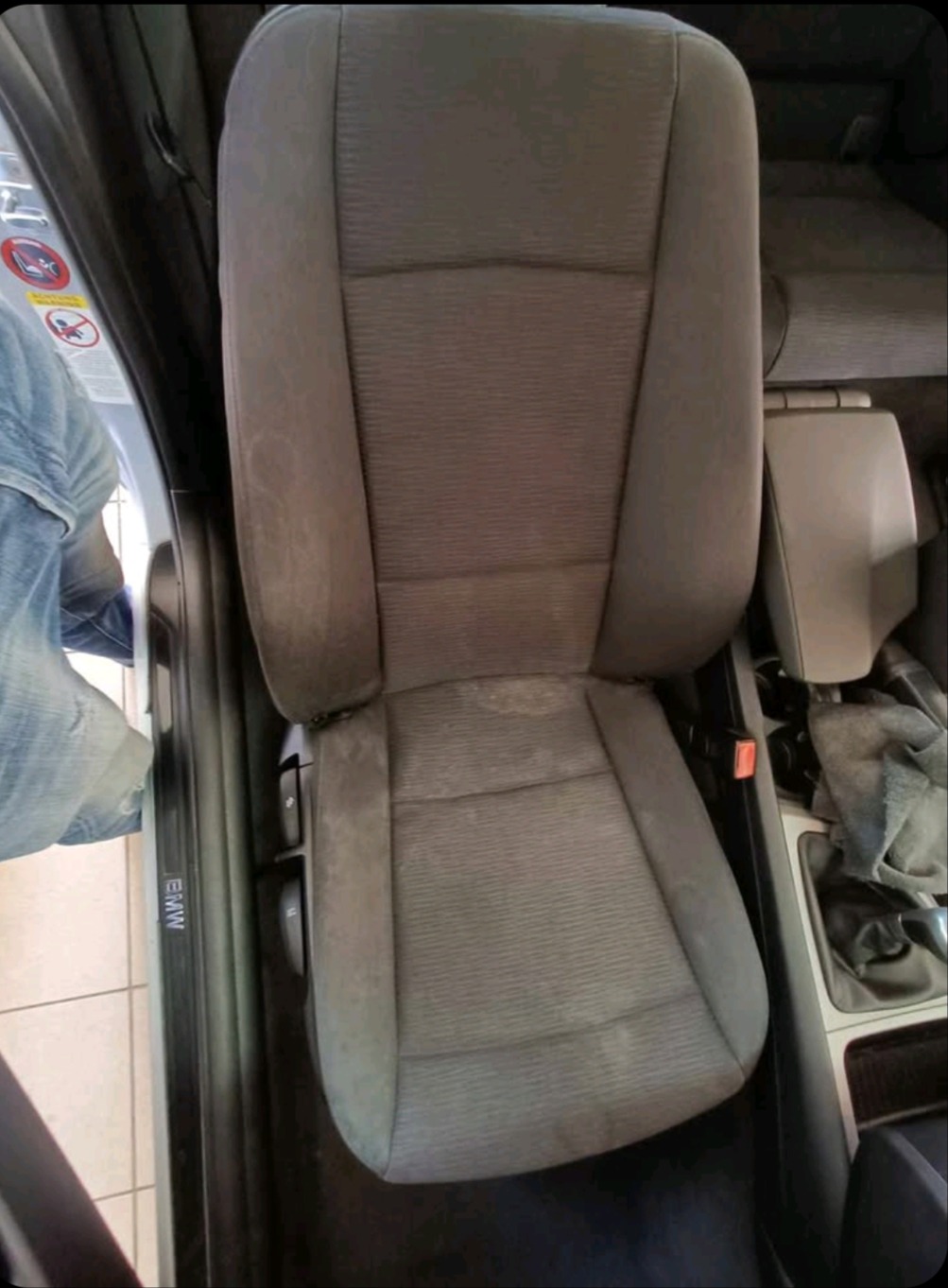 Brudny, szary fotel samochodowy BMW z widocznymi plamami i zabrudzeniami, wnętrze auta. Fotel przed czyszczeniem tapicerki.