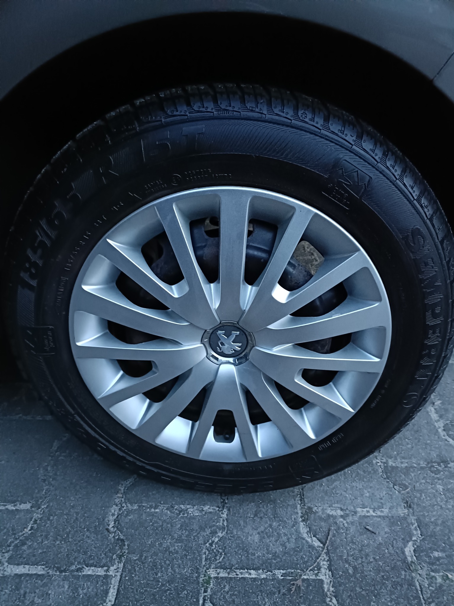 Błyszcząca, czysta opona Peugeot z aluminiową felgą, widoczny bieżnik i logo marki. Detal po umyciu w myjni.