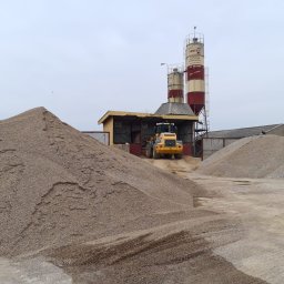 Wytwórnia Materiałów Budowlanych Zdzisława Szczepańska - Żwirownia z hałdami kruszywa i żółtą ładowarką na tle silosów pod pochmurnym niebem.