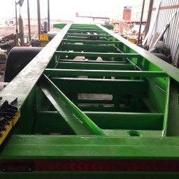 OLIGO Kamil Frankowski - Zielona, metalowa rama przyczepy po piaskowaniu i malowaniu, widoczna struktura kratowa i spawane łączenia, w tle warsztat.