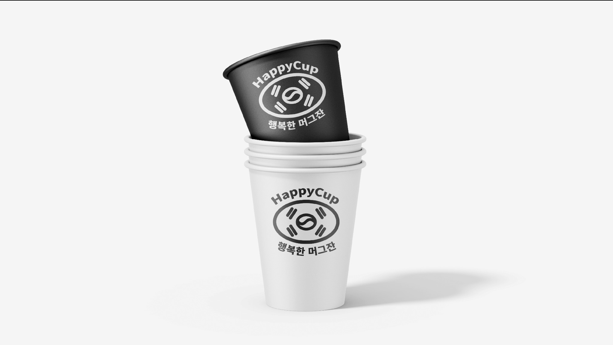 Stos białych papierowych kubków z czarnym kubkiem na górze, każdy z nadrukowanym logo HappyCup i tekstem w języku koreańskim na białym tle.