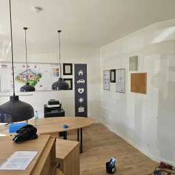 BART-BUD BARTOSZ ŁOŚ WYKOŃCZENIA WNĘTRZ - Przygotowania do malowania biura w Gorzowie Wielkopolskim: widoczne narzędzia, dokumenty i elementy wyposażenia wnętrza przed rozpoczęciem prac malarskich.