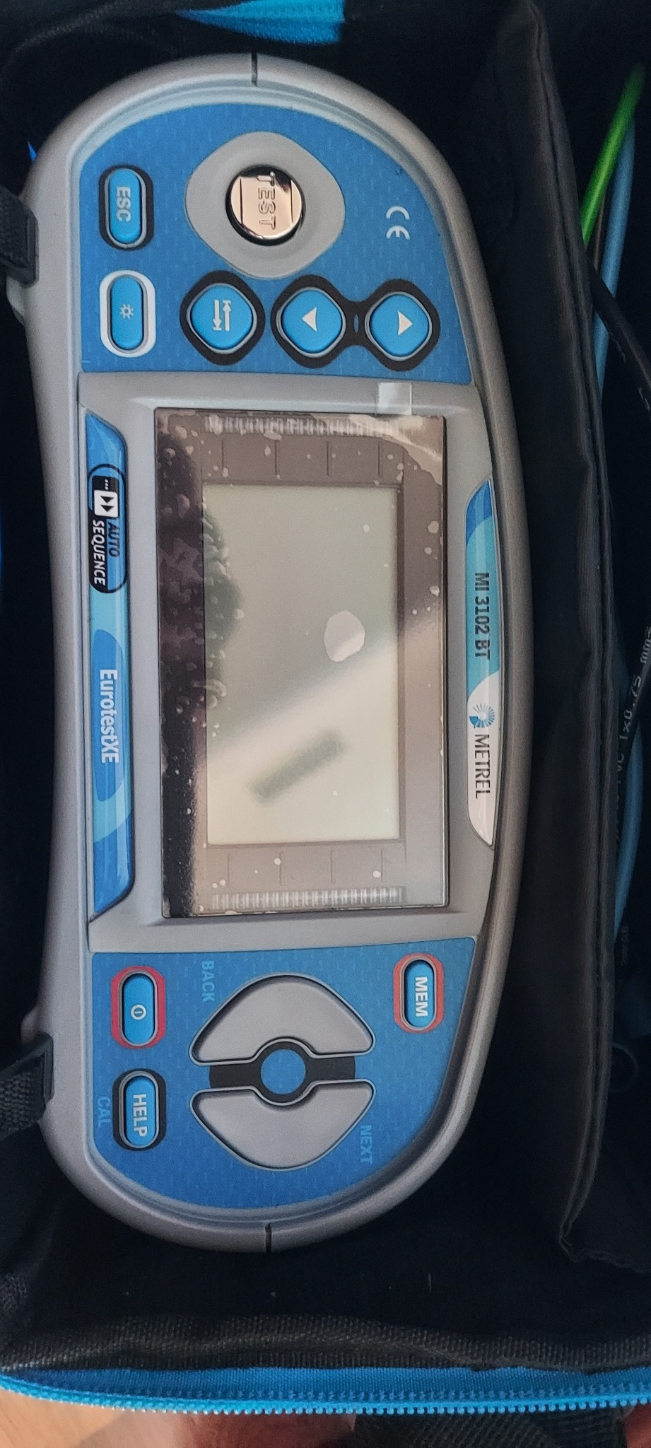 Miernik elektryczny Metrel MI 3102 BT EurotestXE w futerale, widoczne przyciski funkcyjne i zarys ekranu.