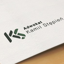 Logo adwokata Kamila Stępnia na teksturowanym, białym papierze. Grafika przedstawia stylizowany symbol 'KS' w odcieniach zieleni, umieszczony obok napisu 'Adwokat Kamil Stępień'.