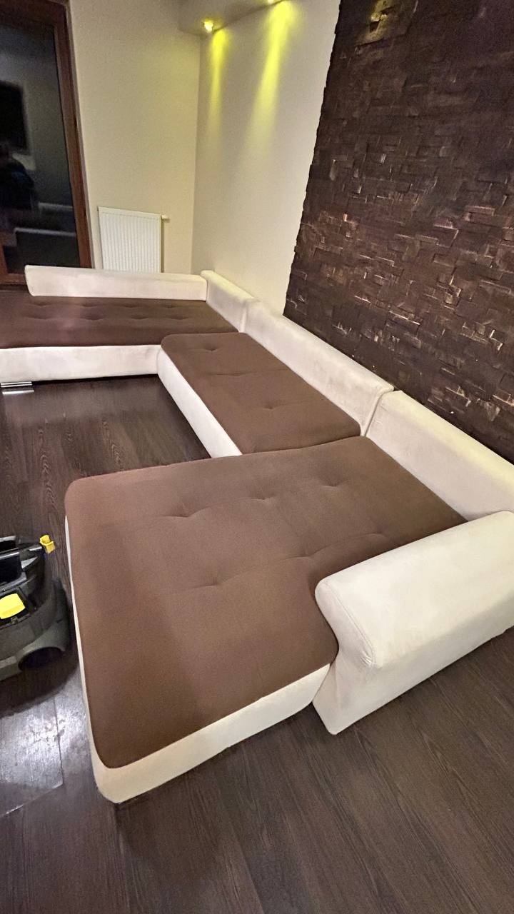 Czyszczenie narożnika z brązowymi siedziskami i jasnymi bokami we Wrocławiu, z widocznym odkurzaczem na podłodze, sugerujące proces czyszczenia.