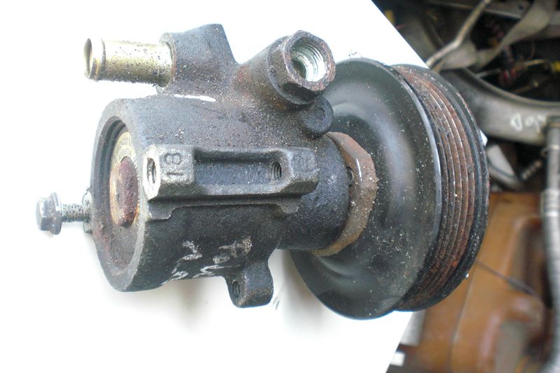 Używana pompa wspomagania układu kierowniczego z kołem pasowym, widoczne ślady eksploatacji i zabrudzenia.