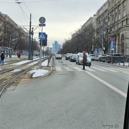 TAXI SEROCK MITER - Taksówka 24h - Postój Taxi - Ulica w mieście z tramwajami, przejściem dla pieszych i jadącymi samochodami, widok z wnętrza pojazdu.