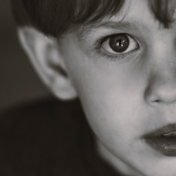 Anna Rucińska - Czarno-białe, portretowe zbliżenie twarzy dziecka, z wyraźnym odbiciem w oku i lekko otwartymi ustami, skierowanymi w stronę światła.