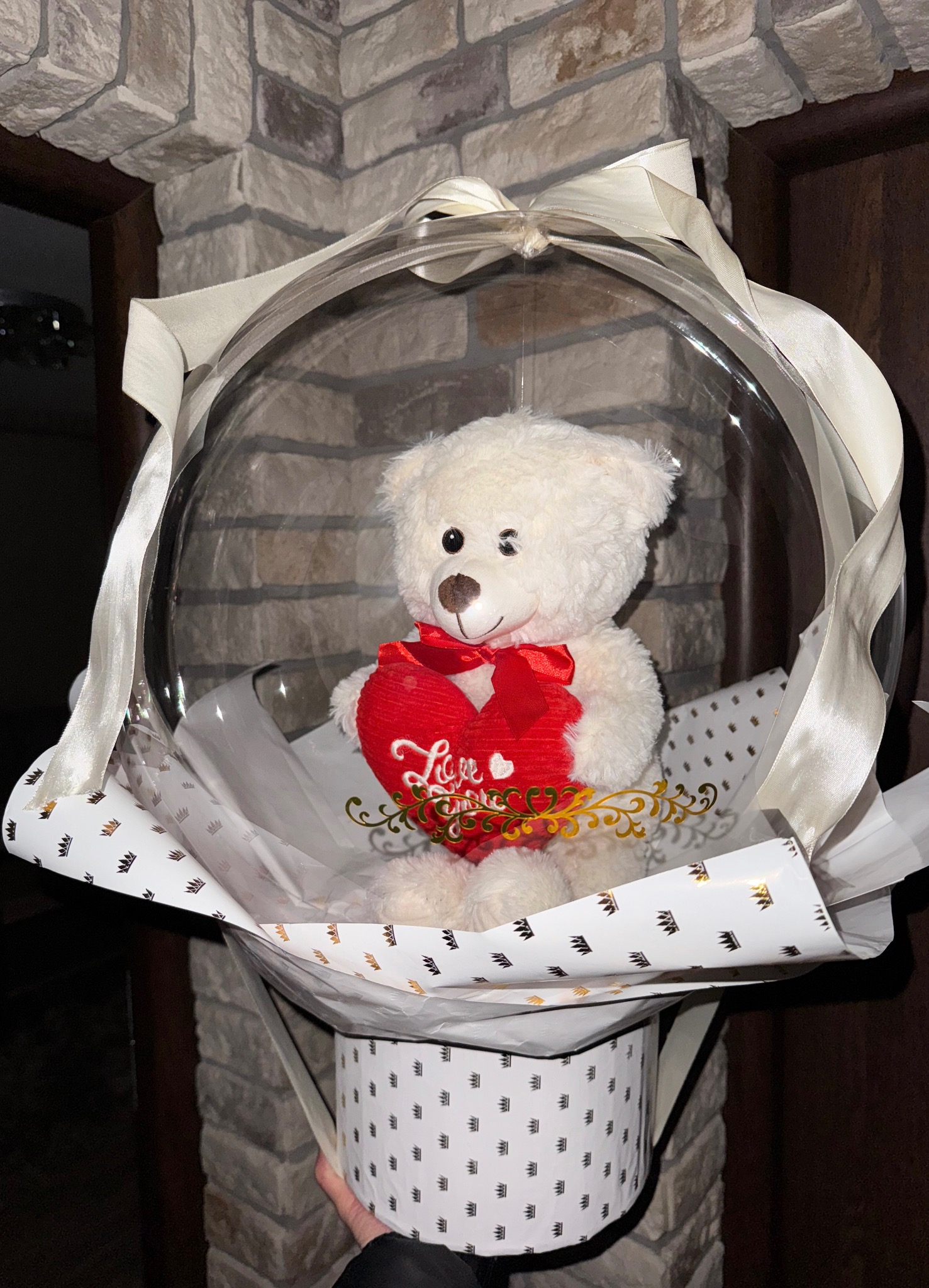 Dekoracja prezentowa z pluszowym misiem w przezroczystej kuli, ozdobiona wstążkami i sercem z napisem 'Love' w Postaszowicach.