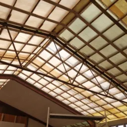 Konstrukcja dachu od wewnątrz z widocznym ociepleniem między krokwiami, rusztowanie i pracownik w tle.