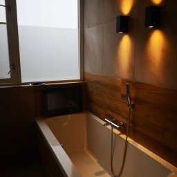 Klusbedrijf Ceasar - Nowoczesna łazienka z wanną, telewizorem w zabudowie, oświetleniem ściennym i oknem z częściowo matową szybą.