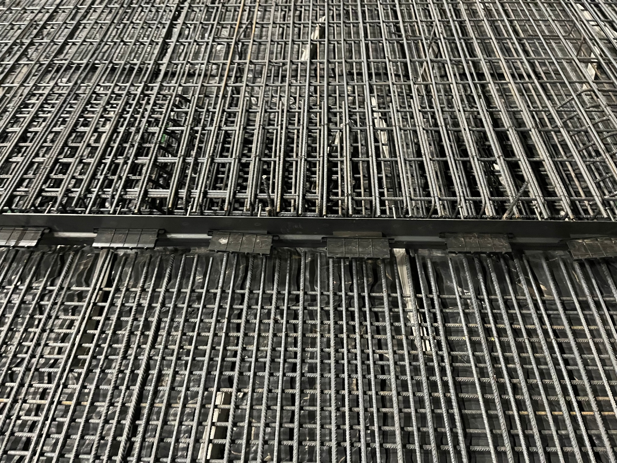Siatka zbrojeniowa ułożona warstwowo, przygotowana do zalania betonem w Gdańsku. Widoczne elementy łączące i folia pod spodem.